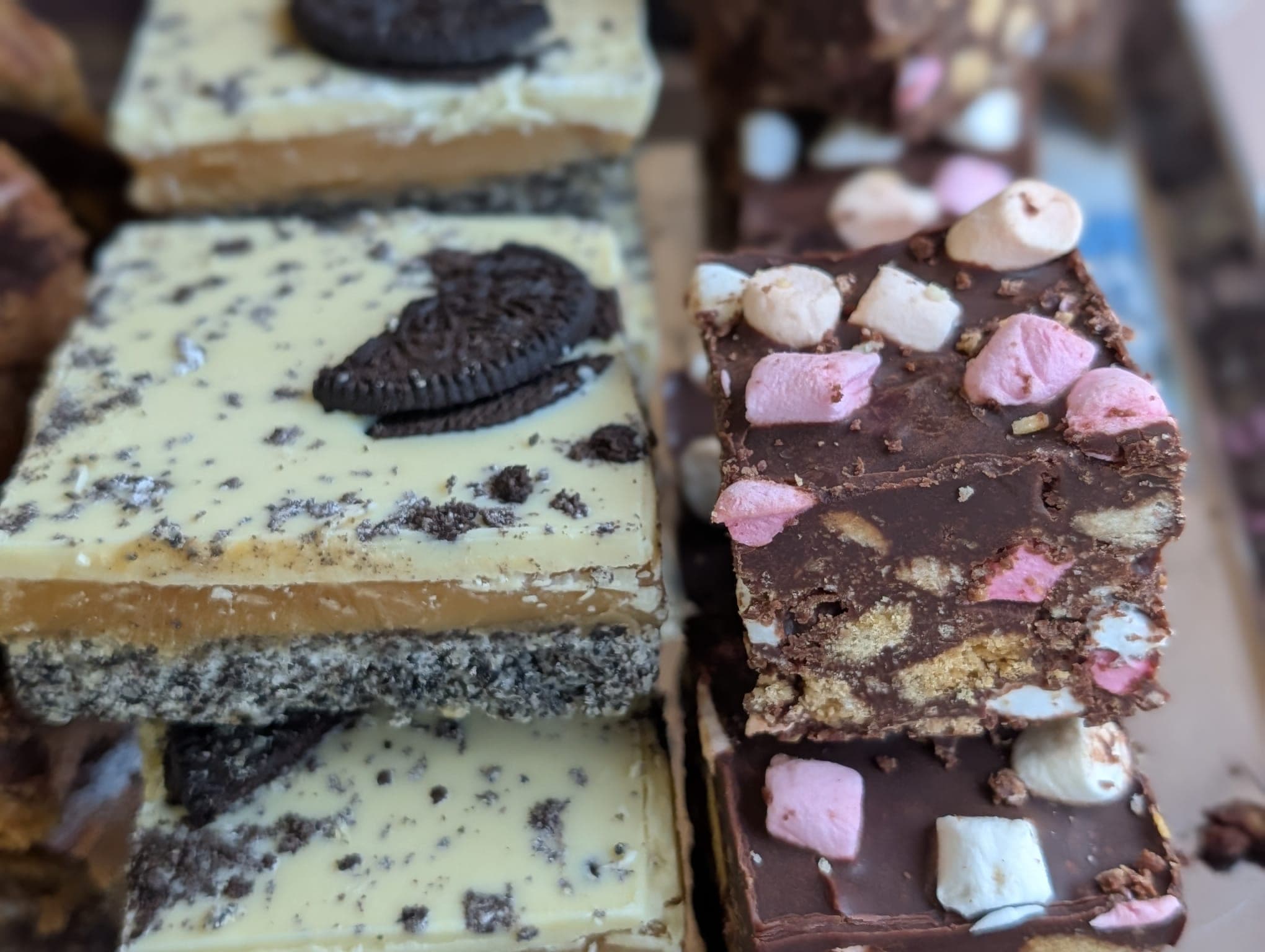 Stacked slices of Oreo millionaire's shortbread beside rocky road topped with marshmallows