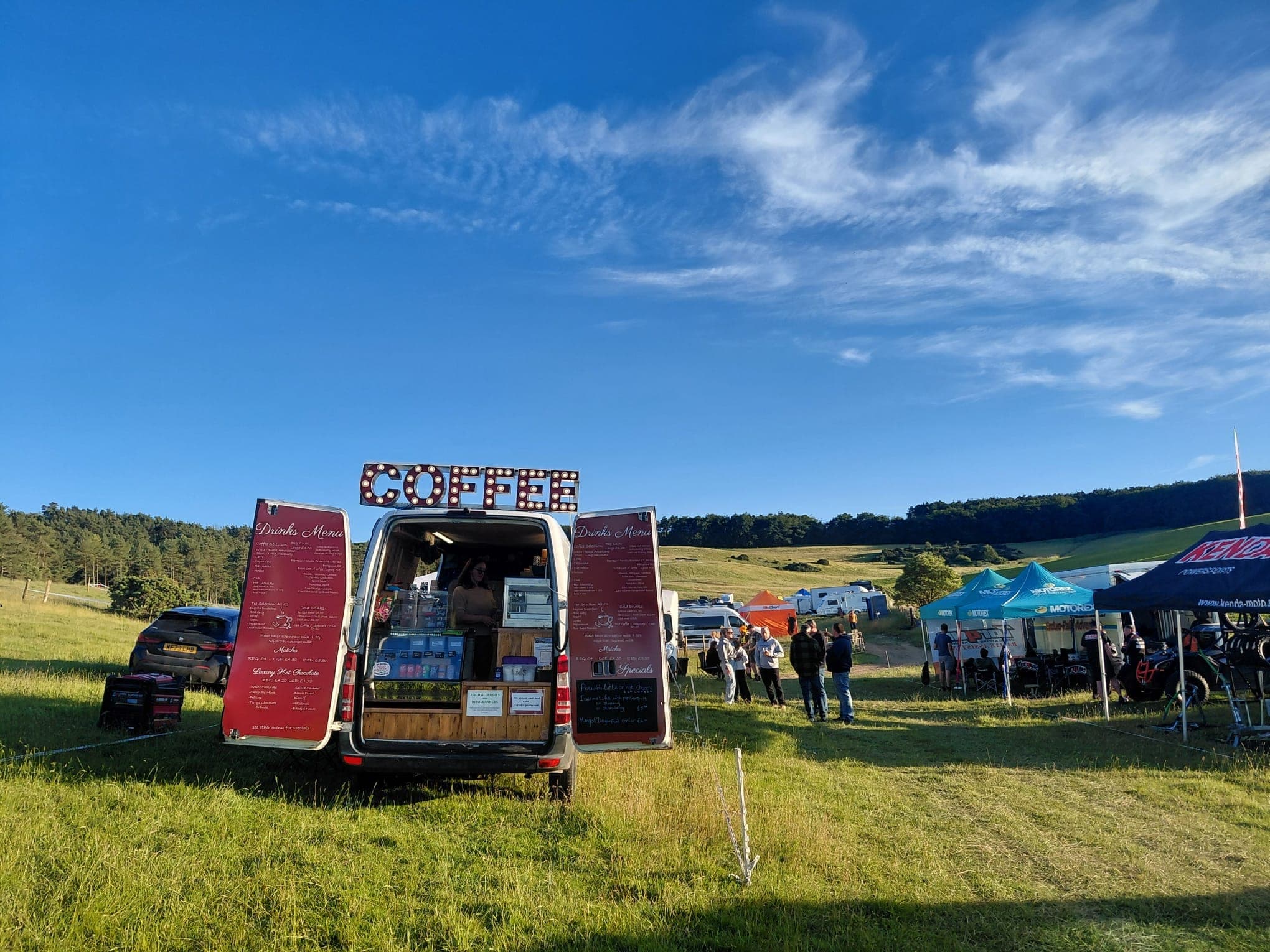 Ahh Roma coffee van open for service at an outdoor countryside event under a vivid blue sky