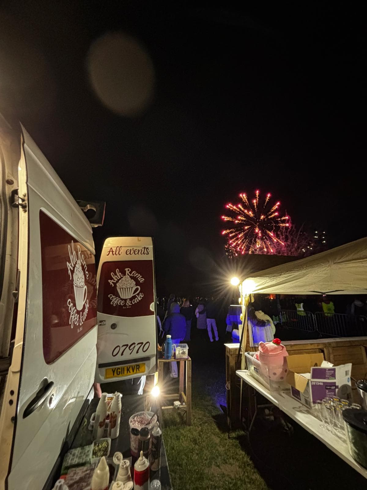 Ahh Roma coffee van set up at a fireworks event at night with red fireworks bursting in the sky above