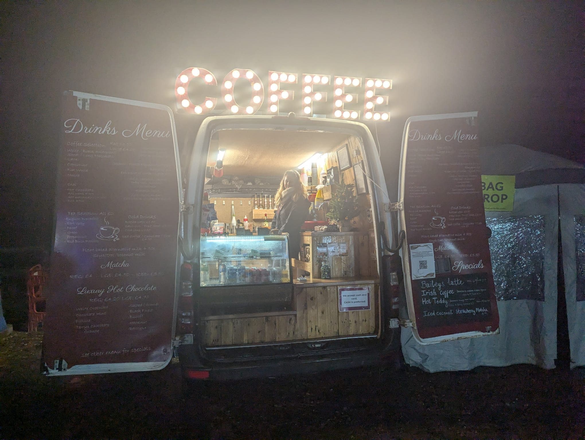 Ahh Roma van lit up at night with COFFEE sign glowing, barista inside serving at a misty evening event